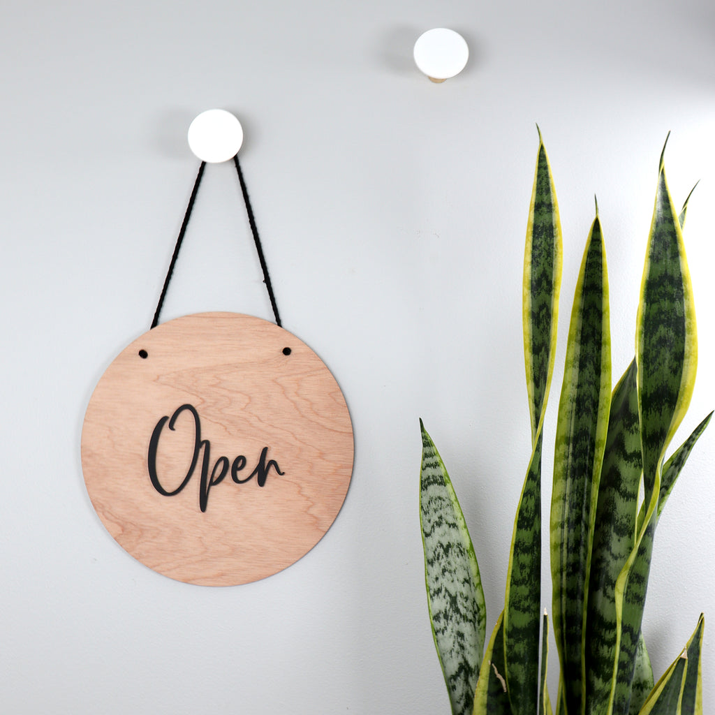 Wooden sign with 'Open' text hanging on a wall. 