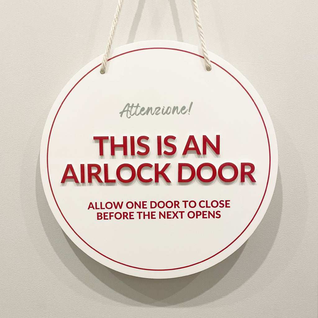 Round coloured acrylic business sign with text 'This is an airlock door' on a plain background. Hanging signs for businesses with bold printed text and 3D acrylic stand-off text.