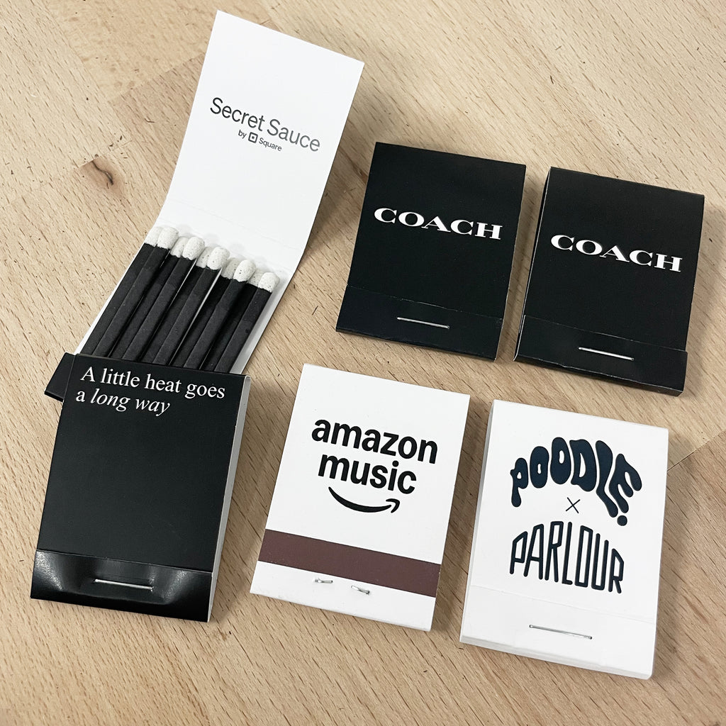 Collection of branded corporate matchbooks including Coach, Amazon Music, and Square.