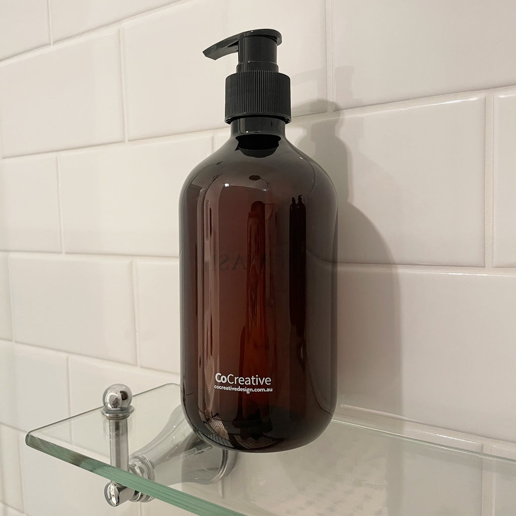 Brown refillable bathroom bottle with CoCreative design branding printed on the back.