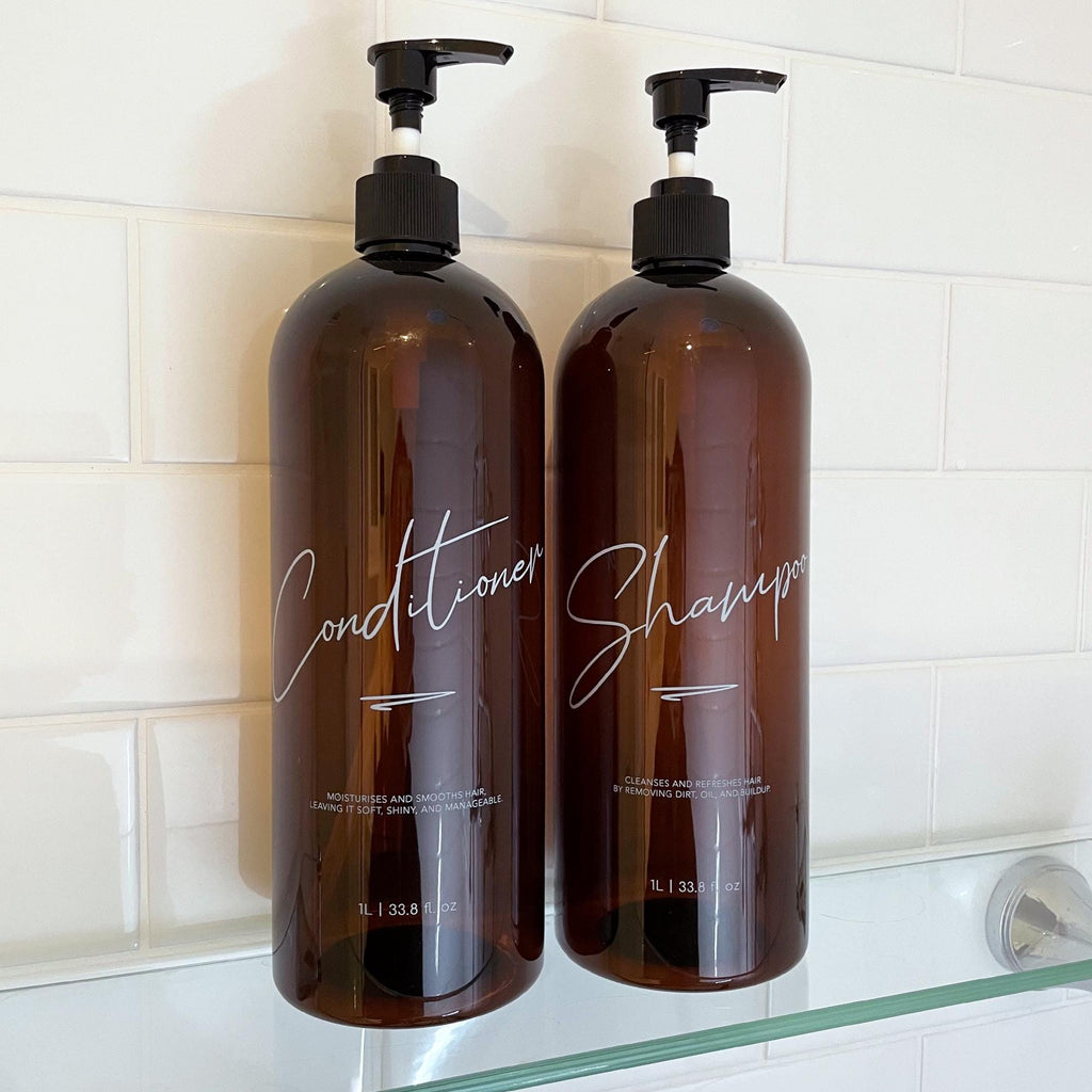 2 piece 1 litre bathroom bottles with elegant cursive design. Custom shampoo and conditioner refillable bottles. Brown bottle with black pump.