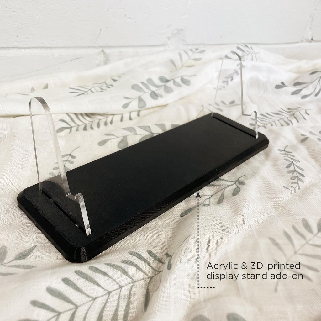 Black acrylic display stand on a white surface with floral pattern
