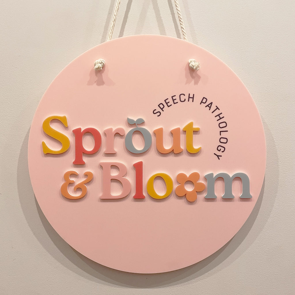 Decorative hanging sign for Speech Pathology business, 'Sprout & Bloom'. 3D acrylic text and business logo on a pink acrylic circle sign.