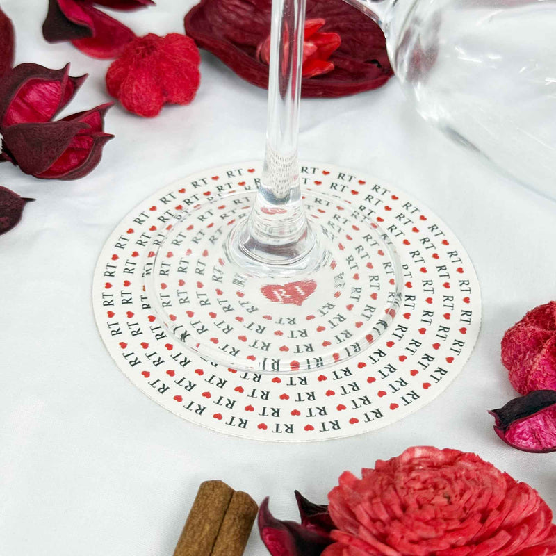 Wine glass sitting on a custom printed round wedding coaster with heart and name design.
