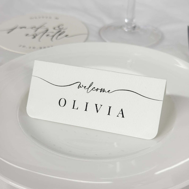 Elegant wedding name place card with "Welcome" cursive design and serif name. Modern, minimalist wedding aesthetic.